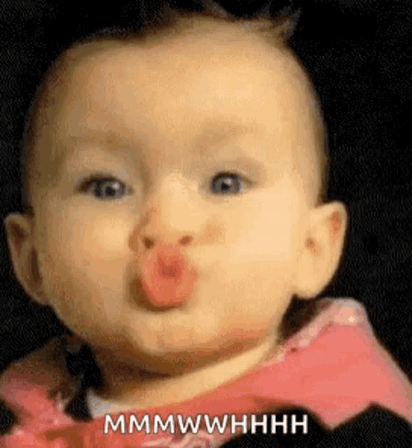 a baby is blowing a kiss with his mouth open and making a funny face .