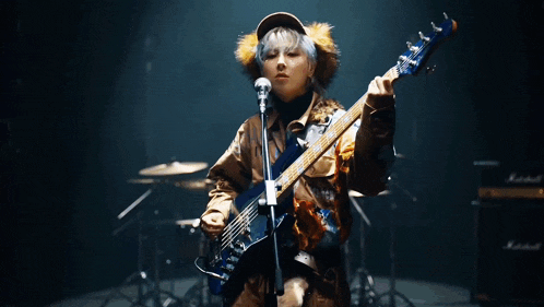 a woman is playing a bass guitar in front of a microphone .