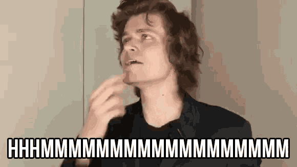 a man in a suit is making a funny face while talking on a microphone .