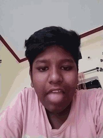 a young boy wearing a pink shirt is making a face
