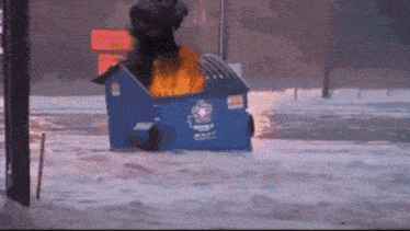 a blue dumpster with a fire coming out of the top
