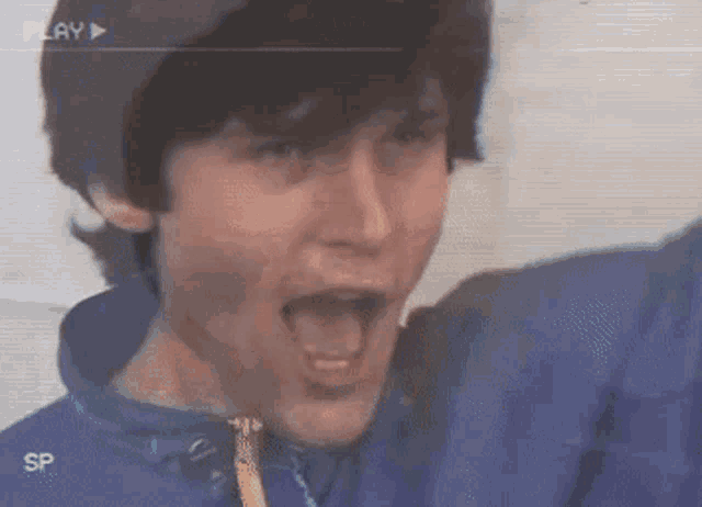 a man in a blue jacket is making a funny face in a video that says play sp