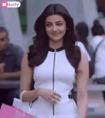 a woman in a white and black dress is holding a pink bag and smiling .