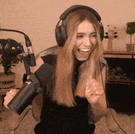 a woman wearing headphones and holding a microphone laughs