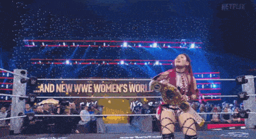 a woman in a wrestling ring with a sign that says " and new we women 's world champions "