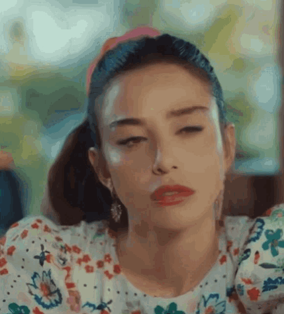 a woman in a floral shirt is making a funny face .