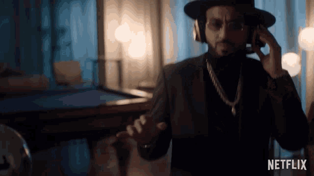 a man wearing a hat and headphones is standing in front of a pool table with netflix written on the bottom
