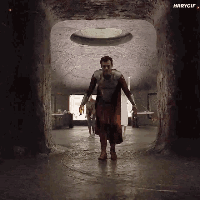 a man in a superhero costume is walking through a tunnel in a cave .