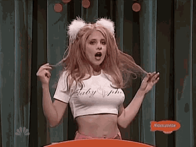 a woman is standing on a stage wearing a crop top and a wig .