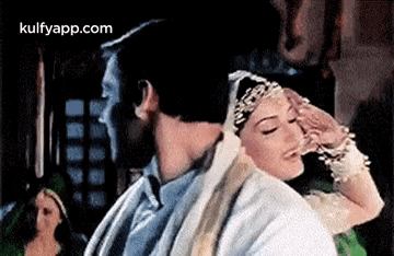a man and a woman are standing next to each other . the woman is holding the man 's head .