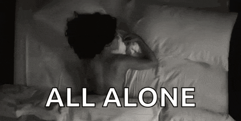 a woman is laying on a bed with the words all alone above her .