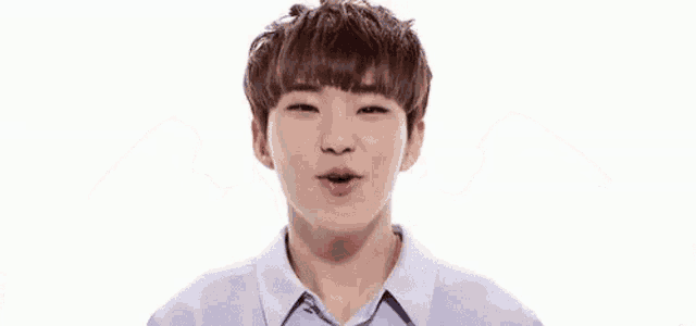 a young man in a purple shirt is making a funny face with his hands .