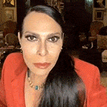 a woman wearing a red jacket and a necklace is looking at the camera .