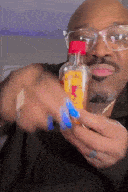 a man wearing glasses is holding a small bottle with a yellow label that says ' honey ' on it