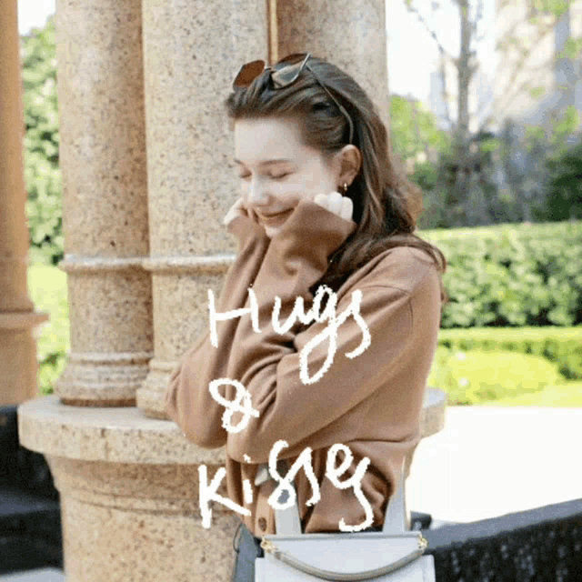 a woman in a brown sweater with the words hugs & kisses written on it