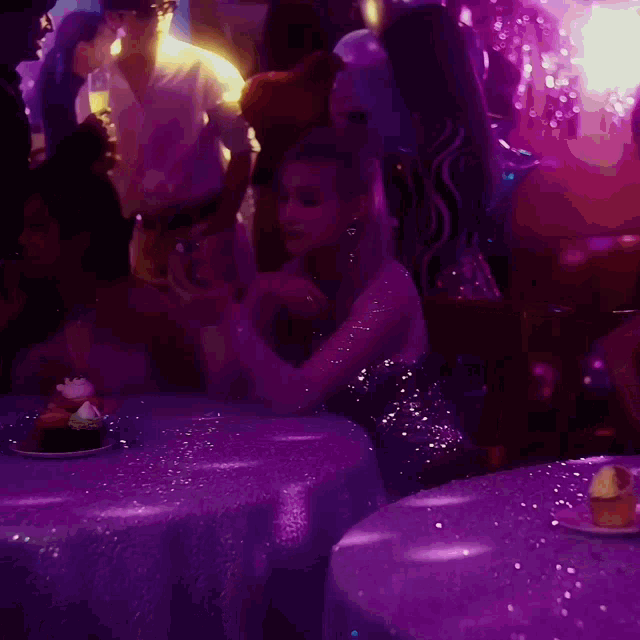 a woman in a sequined dress sits at a table