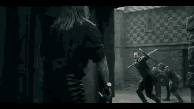 a man is holding a sword while another man holds a sword .