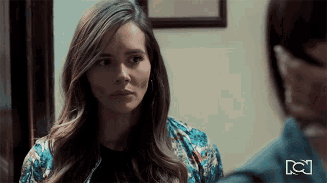 a woman in a floral jacket is looking at a man in a blue shirt