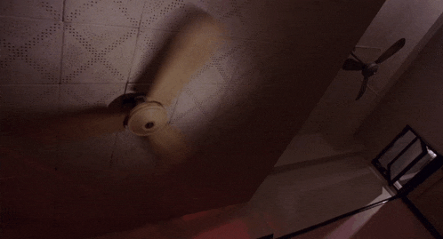 a ceiling fan in a dark room with a light on
