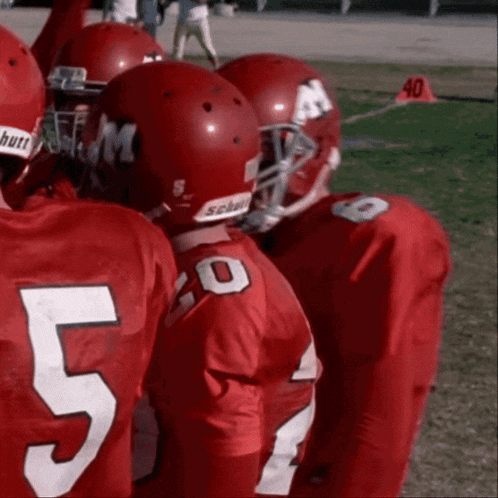 a group of football players wearing red uniforms with the number 5 on their backs