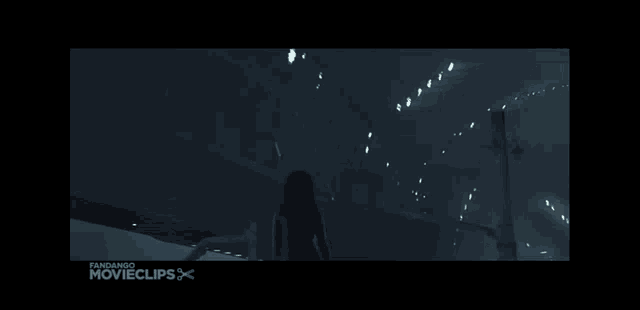 a woman is walking down a dark hallway with the words fandando movieclips below her