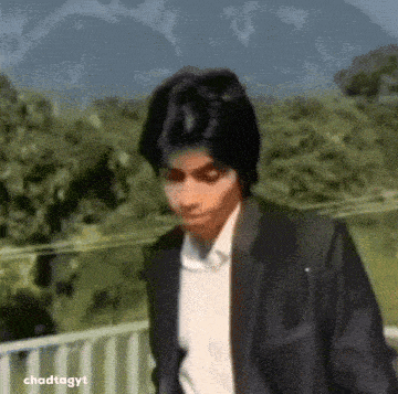 a man in a suit is standing in front of a mountain .