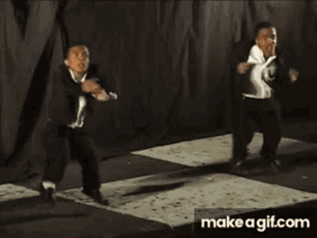 two young men in suits are dancing on a stage .