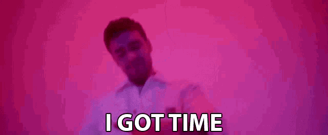 a man is standing in front of a pink background and says `` i got time '' .
