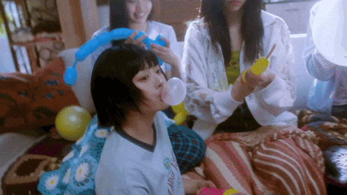 a girl blowing a bubble while wearing a shirt that says ' a ' on it