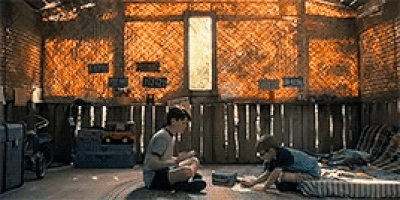 two young boys are sitting on the floor in a room with a sign that says ' a ' on it .