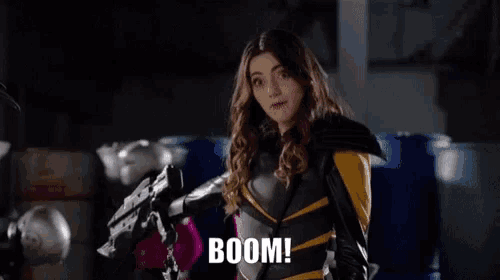 a woman in a superhero costume holds a gun and the word boom is on the screen behind her