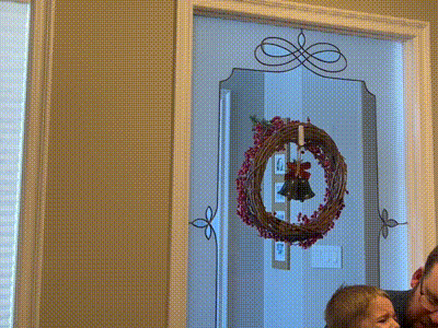 a christmas wreath hangs on a door with a bow
