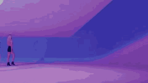 a group of people are dancing in a purple and blue room .