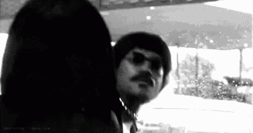 a black and white photo of a man with a mustache wearing sunglasses .