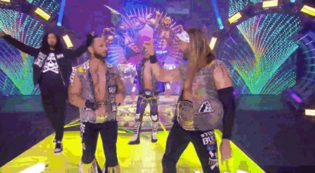 a group of wrestlers are standing on a stage with their arms outstretched .