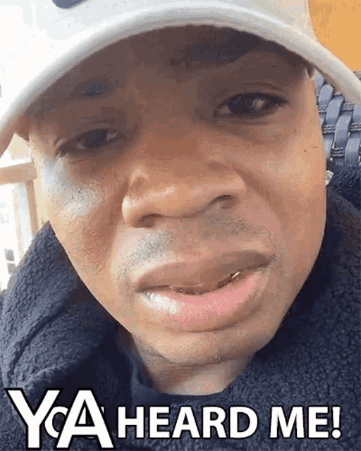 a man wearing a hat says " ya heard me " at the bottom of his face