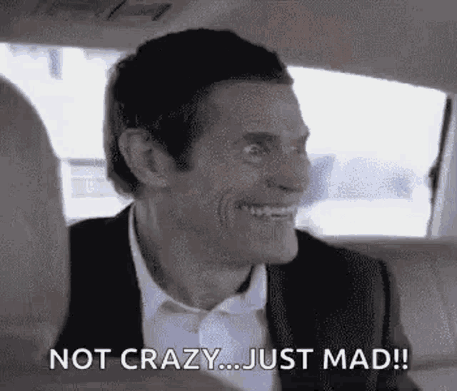 a man in a suit and bow tie is sitting in the back seat of a car .