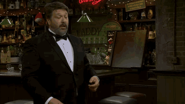 a man in a tuxedo says " i 'd love to get into some " in front of a bar