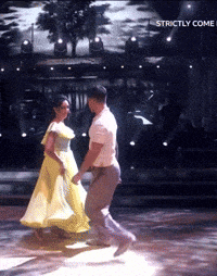 a woman in a yellow dress is dancing with a man in a white shirt