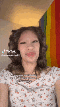 a woman is making a funny face in front of a rainbow flag and says tiktok @ uhmmokayyy22