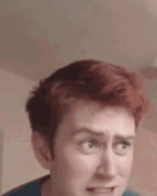 a man with red hair is making a funny face while looking at the camera .