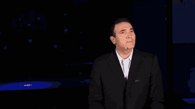 a man in a suit stands in a dark room
