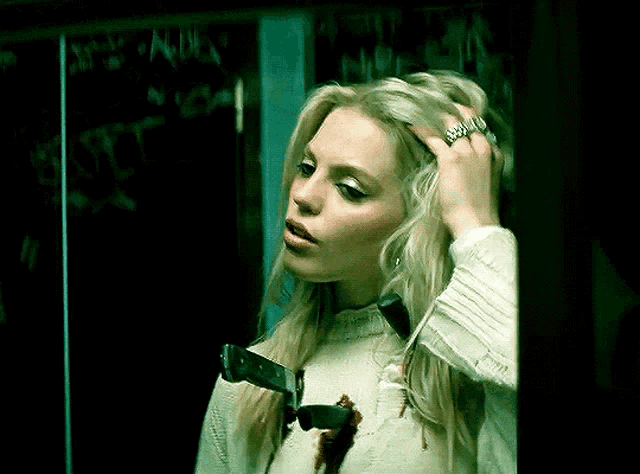 a woman holds a bloody knife around her neck