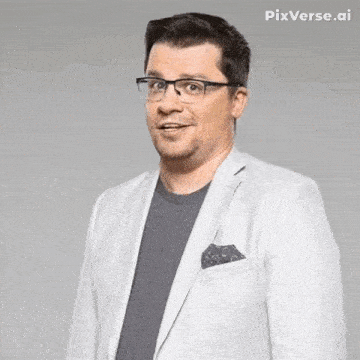 a man wearing glasses and a white jacket is standing in front of a grey background .