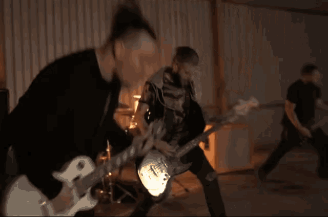 a man in a black shirt is playing a guitar