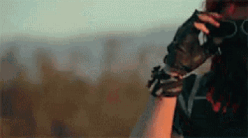 a woman wearing gloves is standing in a field with a sword in her hand .
