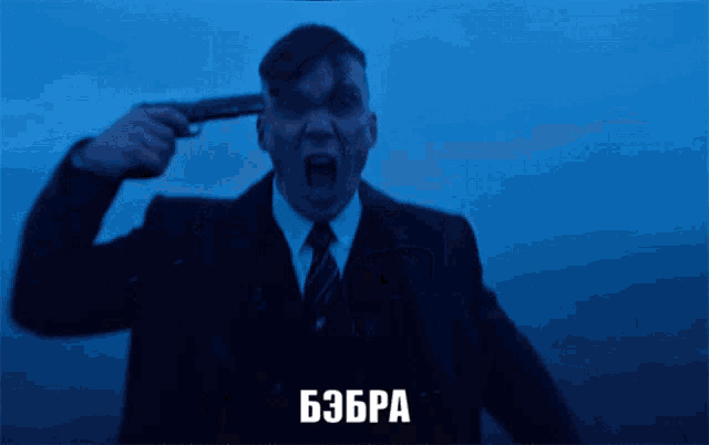 a man in a suit and tie is pointing a gun at his head in a dark room