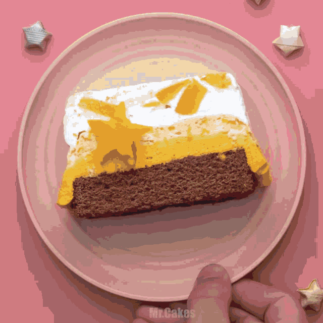 a slice of cake on a pink plate with mr.cakes written on the bottom