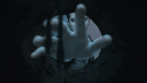 a person 's face is visible through the fingers of a person 's hand