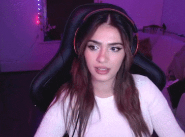 a woman wearing headphones is sitting in a gaming chair and looking at the camera .